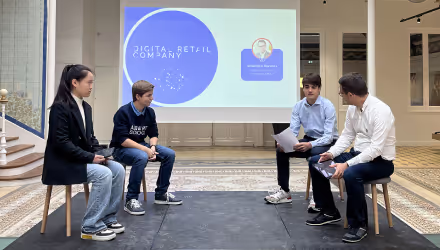 Four people seated on stools in a discussion in front of a screen displaying a digital retail company presentation.
