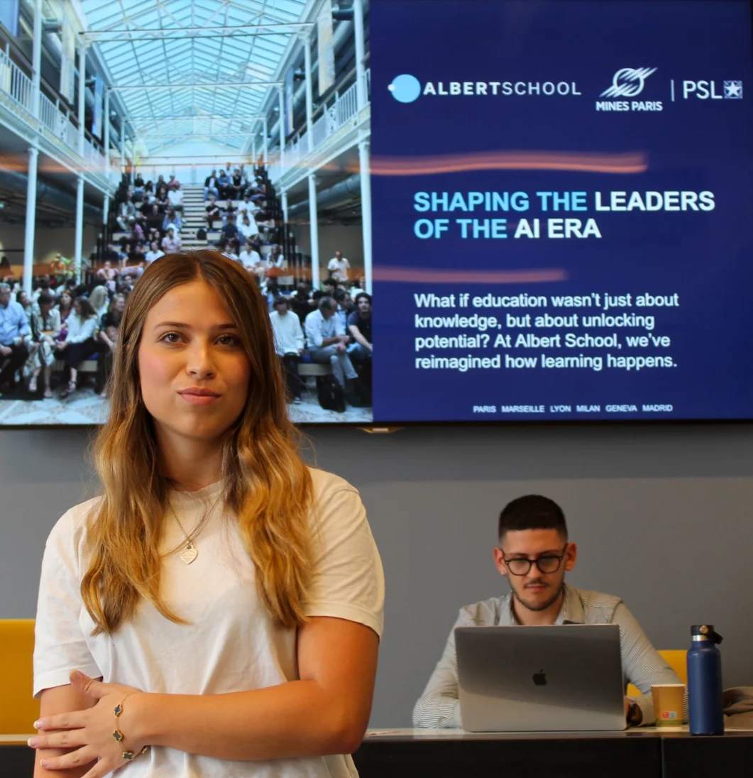 Albert School student in front of a screen reading Shaping the leaders of the AI era
