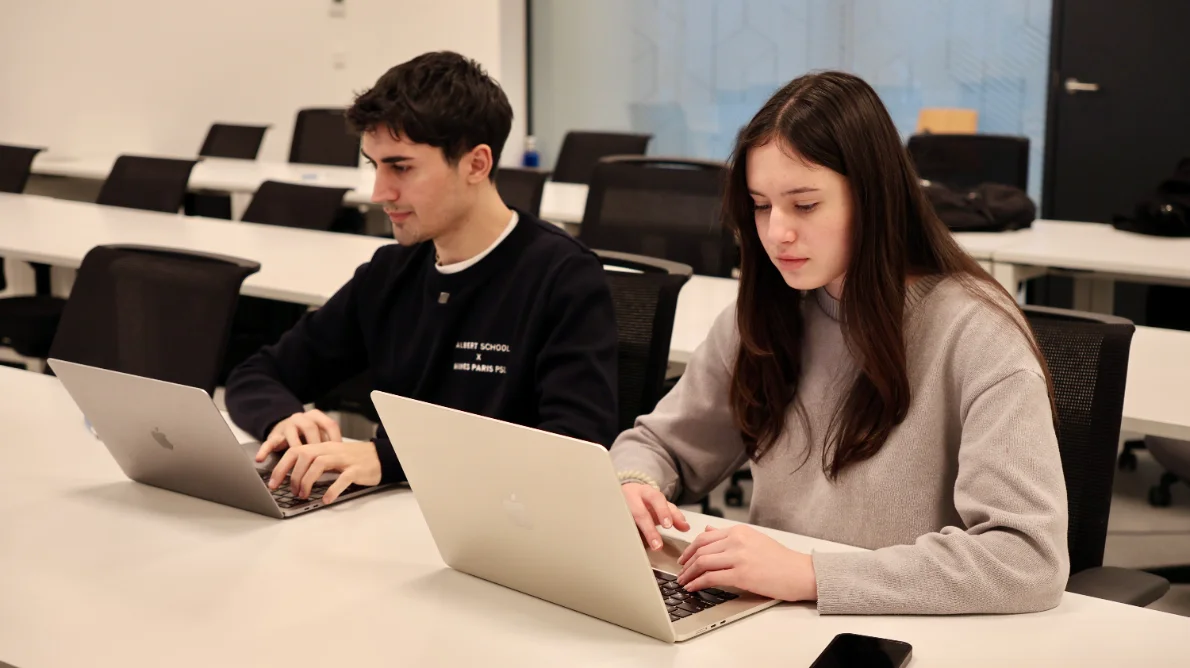 Two Albert School students coding on laptops in class