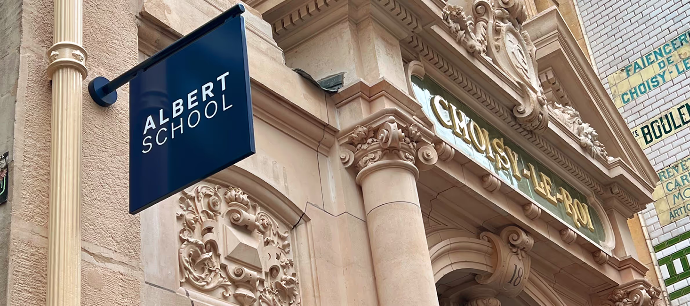 Ornate stone building facade with a blue sign reading 'ALBERT SCHOOL' and gold letters spelling 'CHOISY-LE-ROI'.